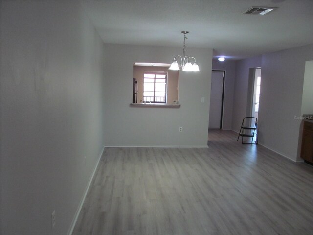 unfurnished room with hardwood / wood-style flooring and an inviting chandelier