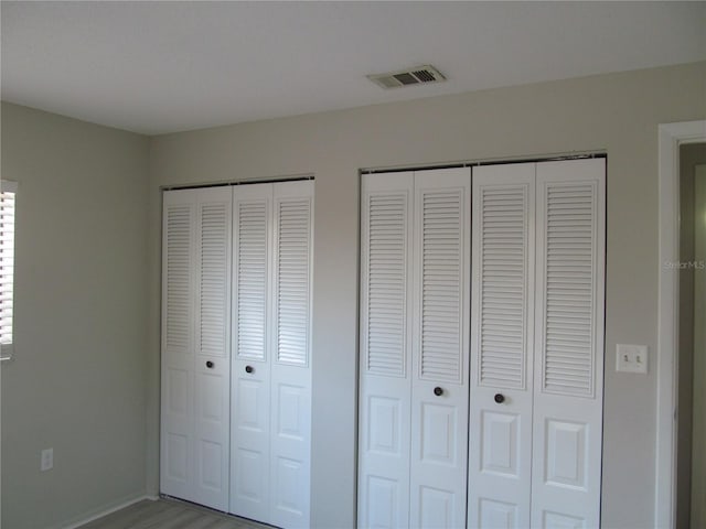 unfurnished bedroom featuring two closets and wood-type flooring