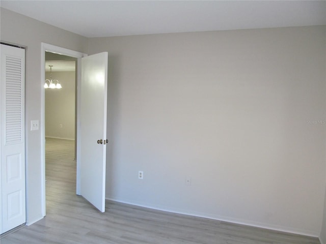 unfurnished bedroom featuring a closet, a chandelier, and light wood-type flooring