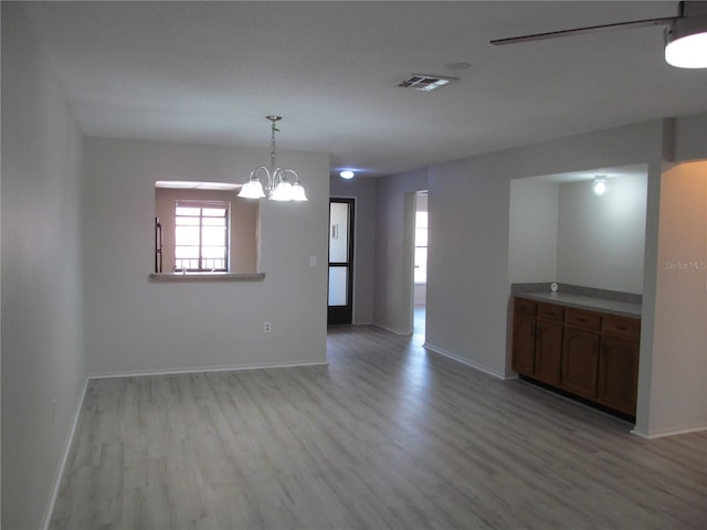 spare room with light hardwood / wood-style floors and a notable chandelier