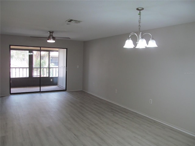 spare room with ceiling fan with notable chandelier and light hardwood / wood-style flooring