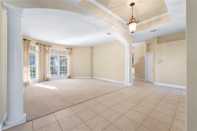 empty room featuring light carpet, ornate columns, and a raised ceiling