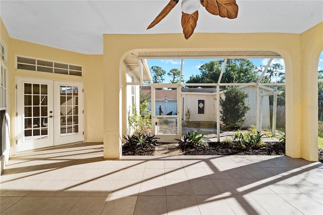 unfurnished sunroom featuring ceiling fan and french doors