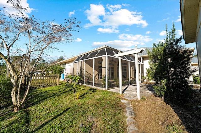 back of property with a yard, glass enclosure, and a patio