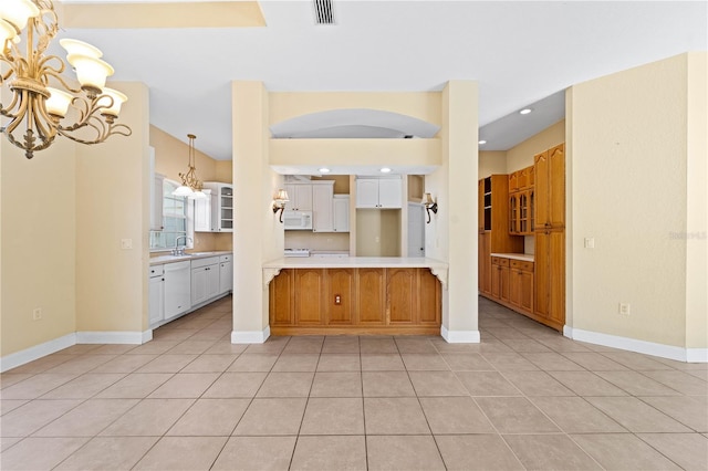 kitchen featuring white appliances, pendant lighting, white cabinets, light tile flooring, and an inviting chandelier