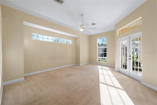 spare room featuring light colored carpet, ceiling fan, and french doors