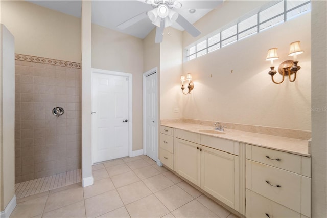 bathroom with a tile shower, vanity, ceiling fan, and tile flooring