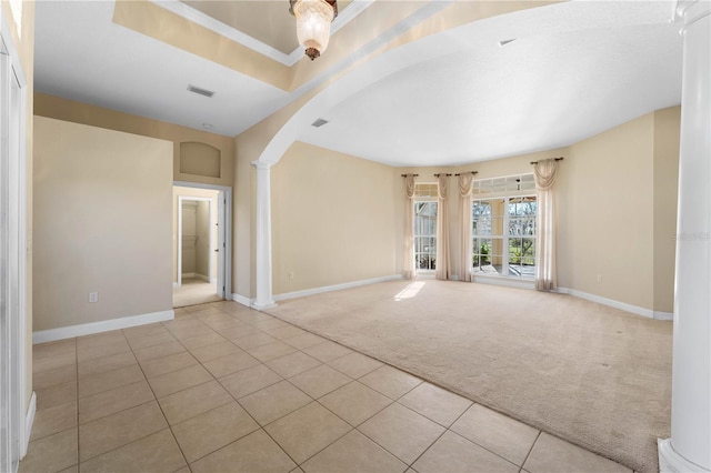 carpeted empty room featuring a tray ceiling and ornate columns