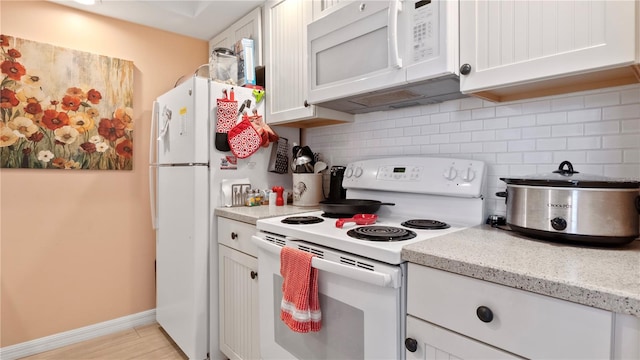 kitchen with tasteful backsplash, white appliances, white cabinets, and light stone counters