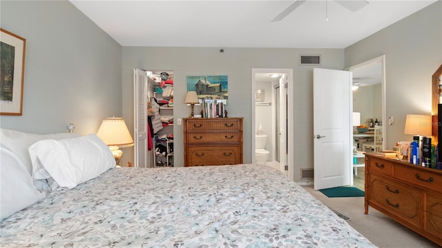 bedroom featuring ceiling fan, a closet, light colored carpet, and ensuite bath