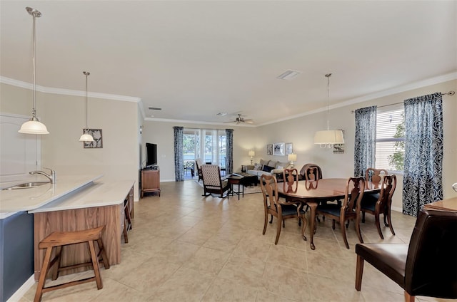 tiled dining space featuring crown molding, ceiling fan, and sink