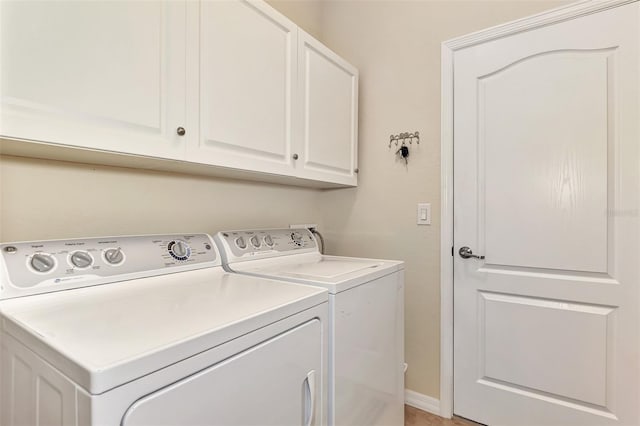 clothes washing area with separate washer and dryer and cabinets