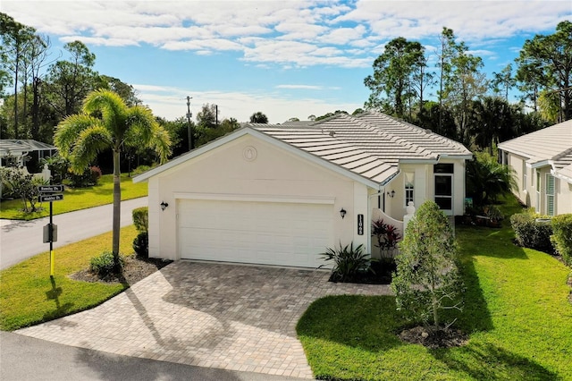 11065 Barnsley Dr, Venice, FL 34293 - ranch-style home featuring stucco siding, decorative driveway, a front lawn, a tile roof, and an attached garage