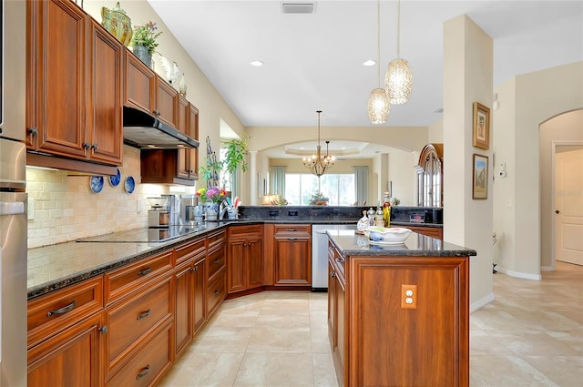 kitchen featuring black electric cooktop, dark stone countertops, pendant lighting, a center island, and an inviting chandelier