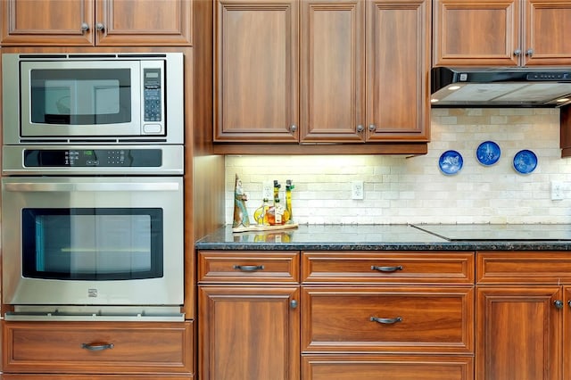 kitchen with dark stone countertops, stainless steel appliances, and backsplash