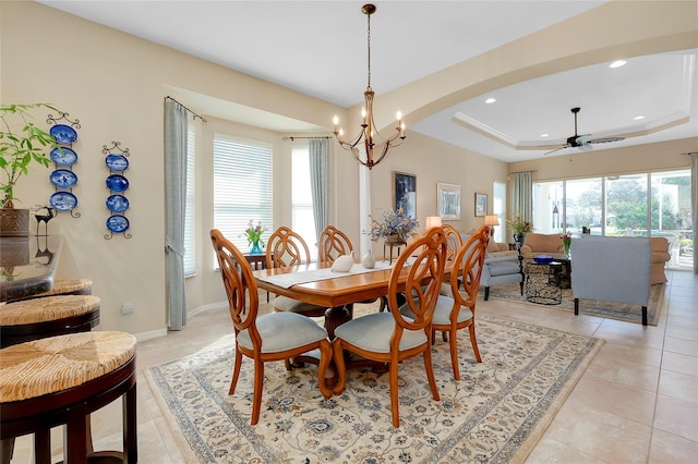 tiled dining room with ceiling fan with notable chandelier, a raised ceiling, and a wealth of natural light