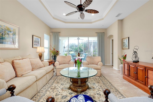 living room featuring ceiling fan, a tray ceiling, and ornamental molding