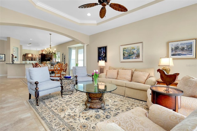 living room featuring ceiling fan with notable chandelier, light tile patterned flooring, crown molding, and a tray ceiling