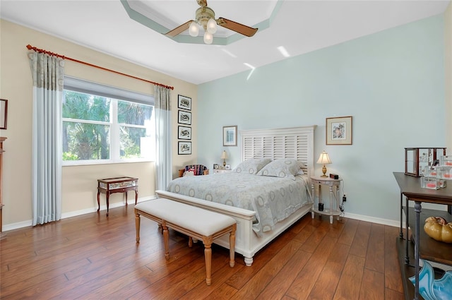 bedroom featuring a raised ceiling, ceiling fan, and hardwood / wood-style flooring