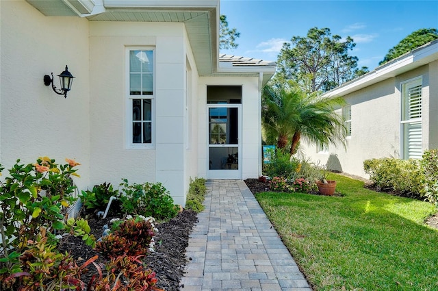 view of exterior entry featuring a lawn