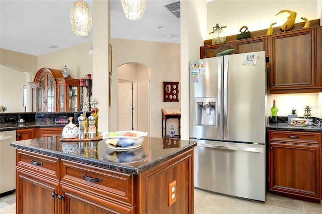 11065 Barnsley Dr, Venice, FL 34293 - kitchen with light tile patterned floors, visible vents, dark stone counters, appliances with stainless steel finishes, and arched walkways