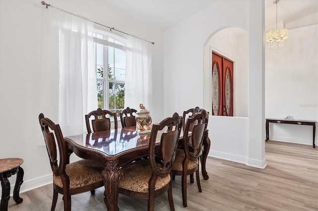 dining space featuring a notable chandelier and light wood-type flooring