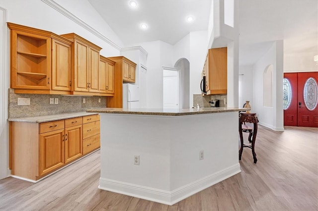 kitchen featuring kitchen peninsula, light hardwood / wood-style floors, light stone counters, tasteful backsplash, and white refrigerator