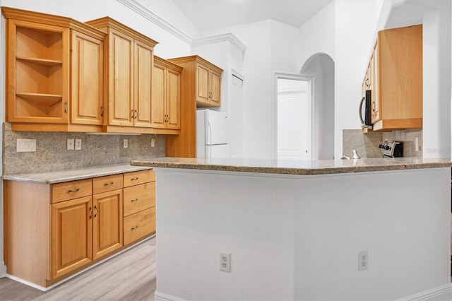 kitchen with light stone countertops, backsplash, white fridge, and light hardwood / wood-style flooring