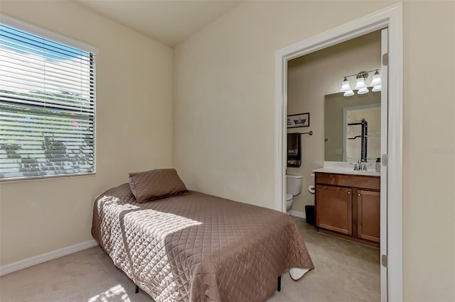 carpeted bedroom with sink and ensuite bath