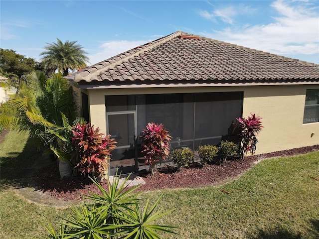 view of side of property featuring a lawn and a sunroom