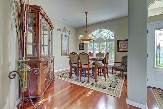 dining area with wood-type flooring and an inviting chandelier