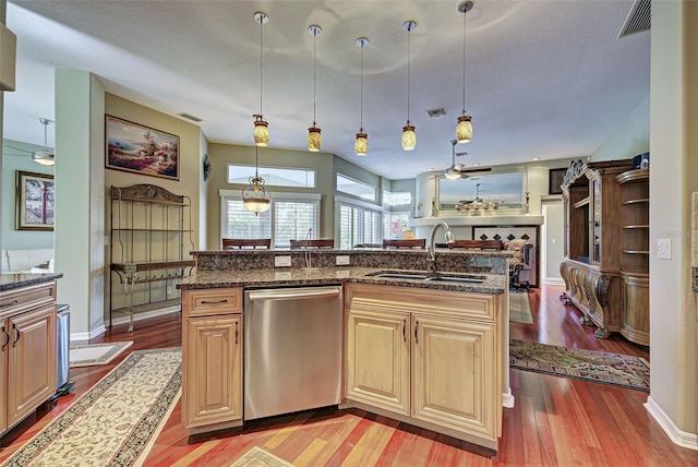 kitchen featuring light hardwood / wood-style floors, sink, dark stone countertops, dishwasher, and pendant lighting