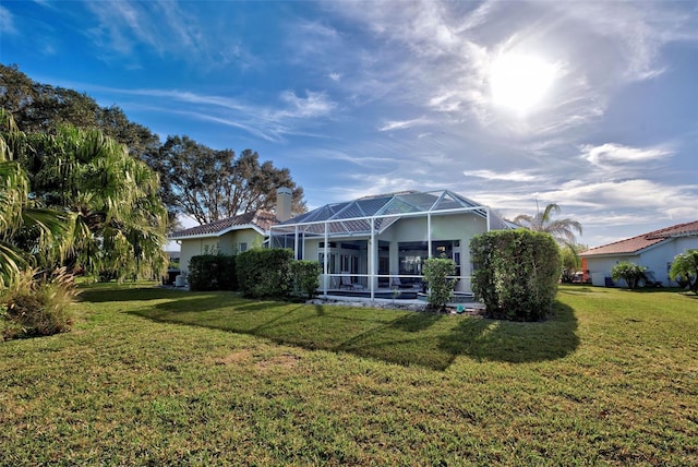 rear view of property featuring a yard and glass enclosure