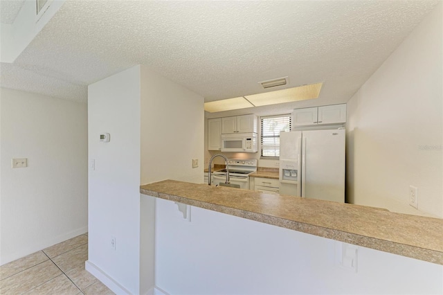 kitchen with white appliances, a textured ceiling, and light tile floors