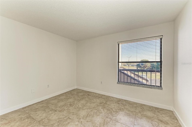 tiled empty room with a textured ceiling