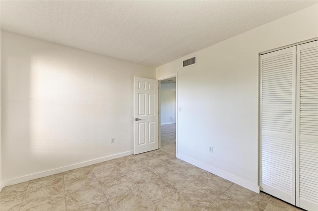 unfurnished bedroom with a closet, a textured ceiling, and light tile flooring