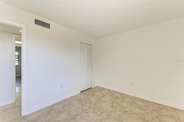 tiled spare room featuring a textured ceiling