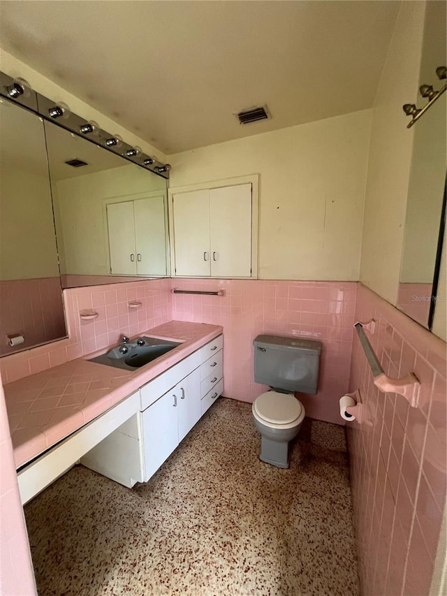 bathroom with backsplash, toilet, vanity, and tile walls