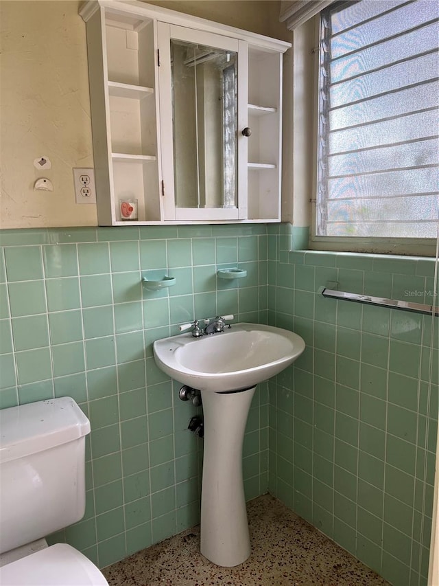 bathroom with tile walls, toilet, backsplash, and a wealth of natural light