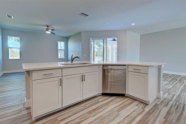 kitchen with a healthy amount of sunlight, stainless steel dishwasher, white cabinetry, and sink