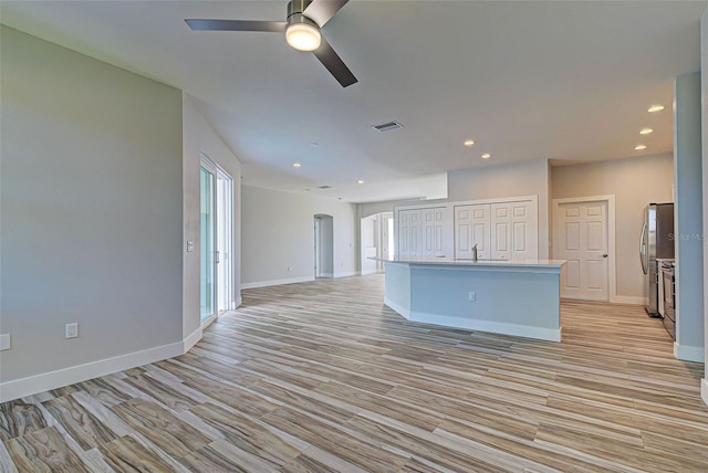 kitchen with a kitchen island with sink, ceiling fan, and sink