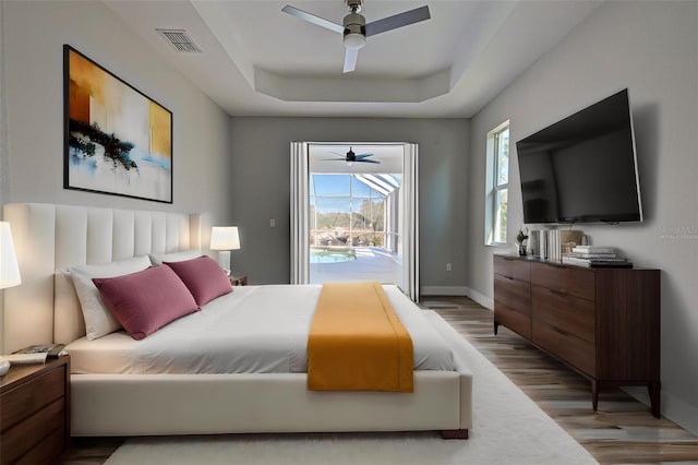 bedroom with a raised ceiling, ceiling fan, access to exterior, and light wood-type flooring