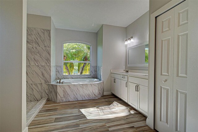 bathroom with vanity and tiled tub