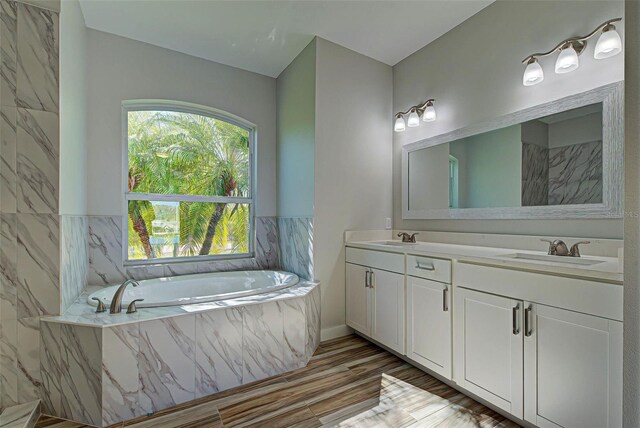 bathroom featuring tiled bath and double vanity