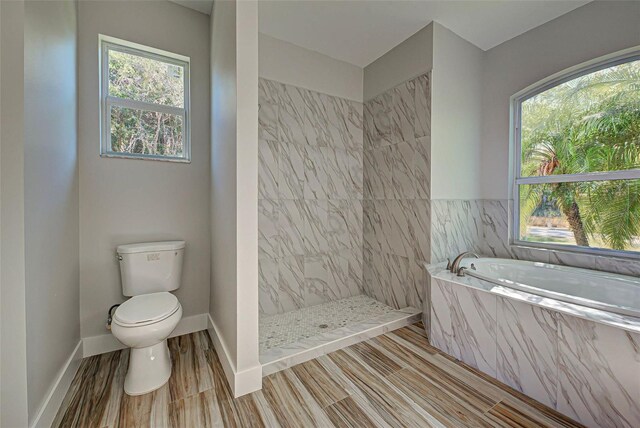 bathroom featuring shower with separate bathtub, tile flooring, a wealth of natural light, and toilet