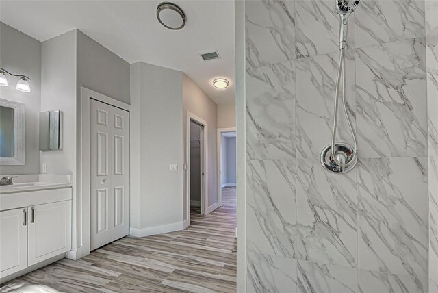 bathroom with a tile shower, vanity, and hardwood / wood-style flooring