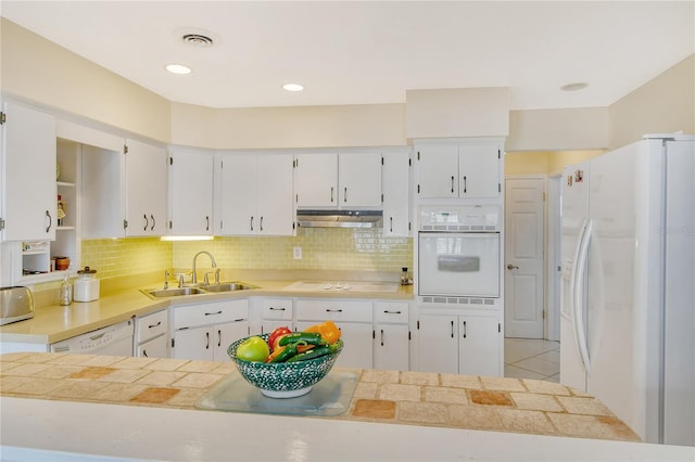 kitchen with tasteful backsplash, white appliances, white cabinets, and sink