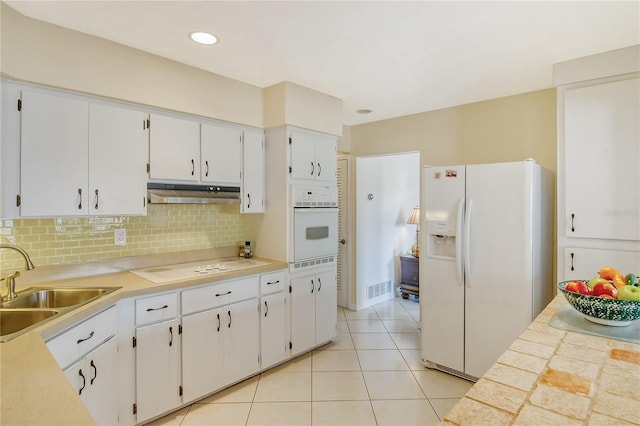 kitchen featuring white appliances, sink, light tile floors, tasteful backsplash, and white cabinetry