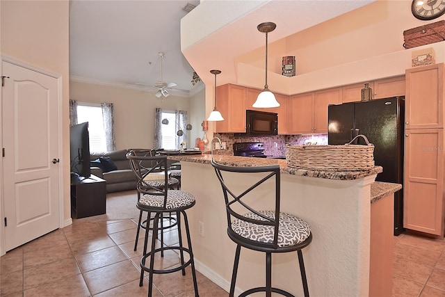 kitchen featuring ceiling fan, hanging light fixtures, backsplash, a breakfast bar area, and black appliances