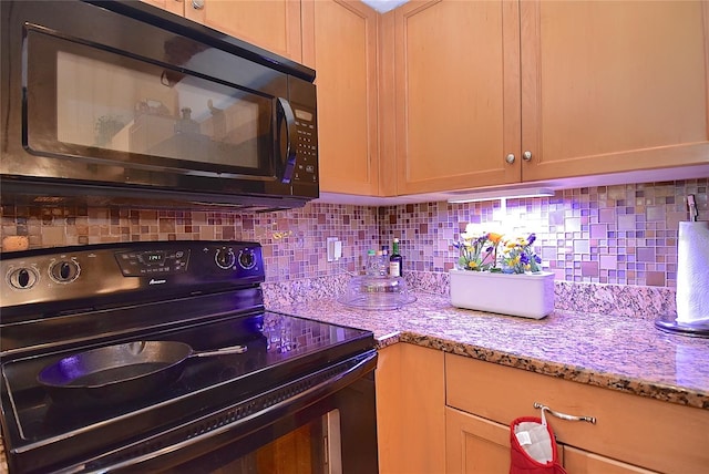 kitchen featuring light stone countertops, tasteful backsplash, and black appliances